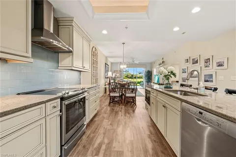 a kitchen with stainless steel appliances granite countertop hardwood floor sink stove dining table and chairs