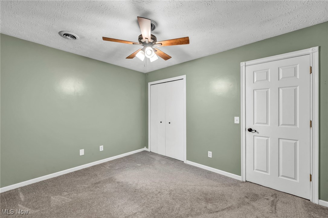 47655 Cooper Foster Park Road Amherst, OH 44001 - Photo 12 of 49 Unfurnished bedroom featuring a textured ceiling, carpet, a closet, and ceiling fan