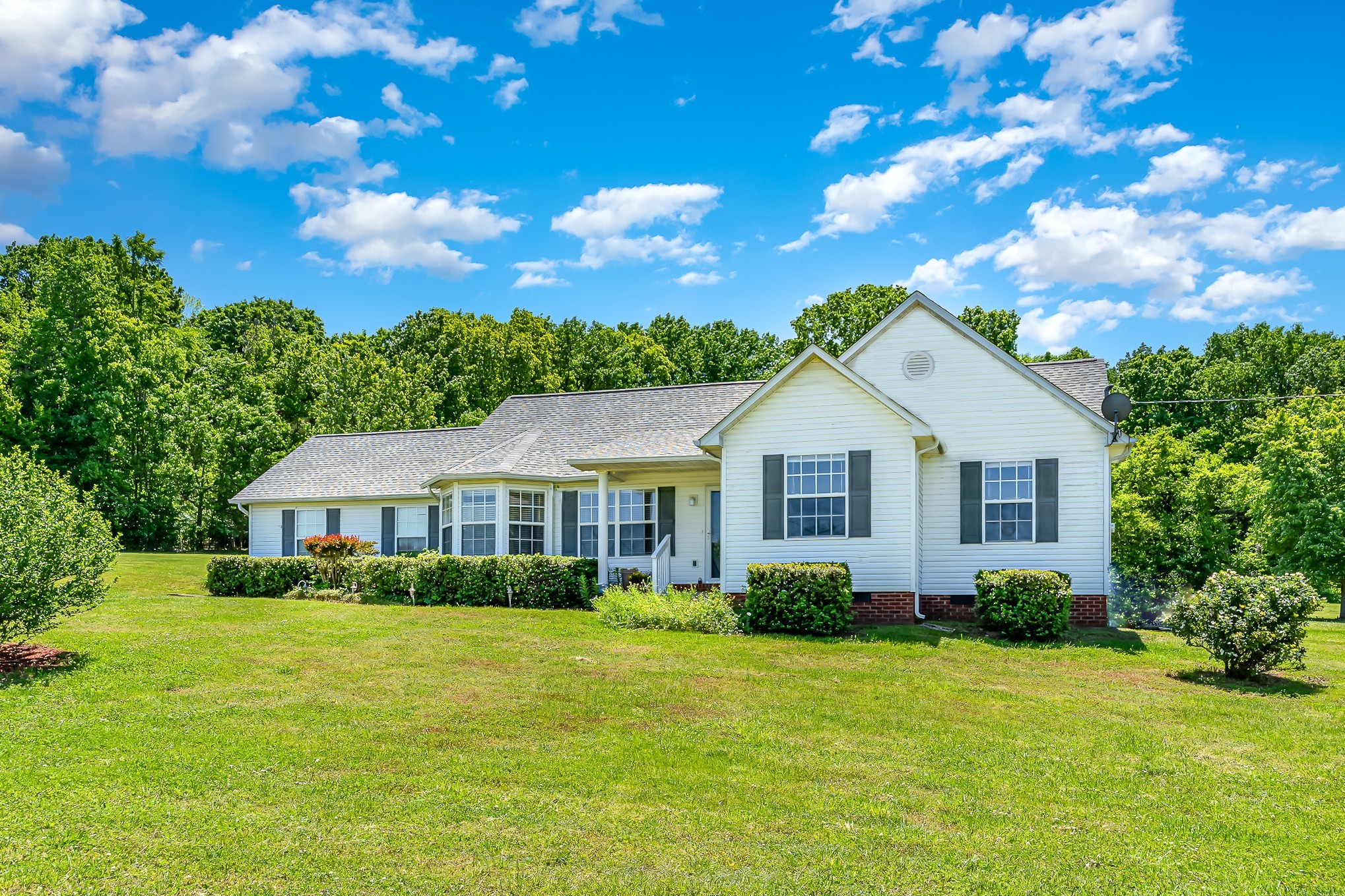 a view of a house with a big yard and large trees