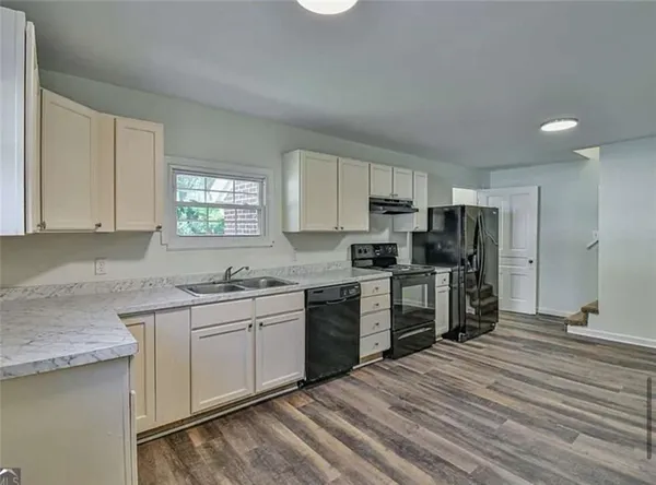 a kitchen with granite countertop a sink stainless steel appliances and white cabinets