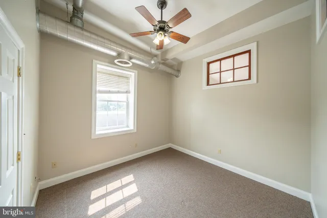 an empty room with windows and fan