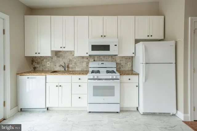 a kitchen with white cabinets and white appliances