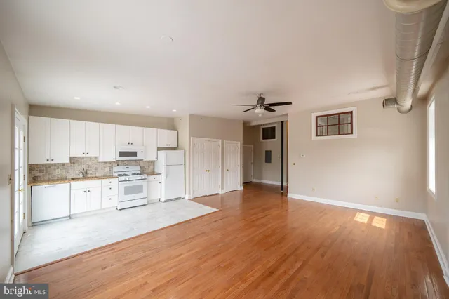 a view of a kitchen with a sink and dishwasher a stove top oven with wooden floor