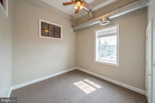 an empty room with a chandelier fan and windows