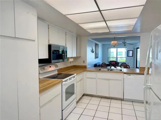 a kitchen with a sink white cabinets and appliances