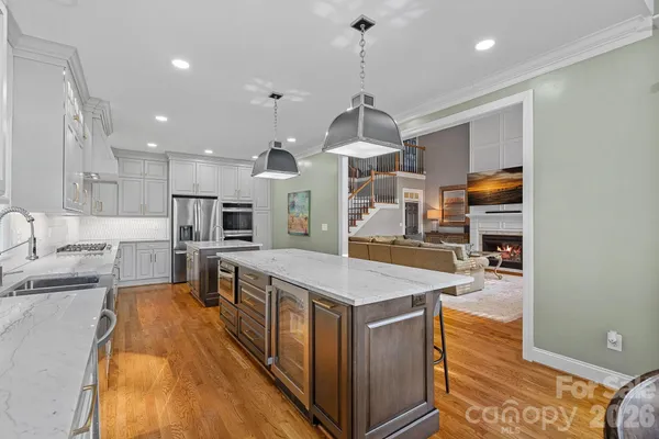 a kitchen with stainless steel appliances granite countertop a sink a stove and a wooden floors