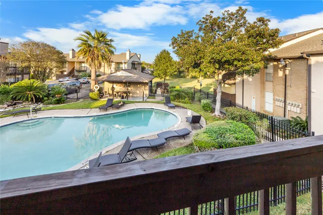 a view of a swimming pool with a lawn chairs under an umbrella