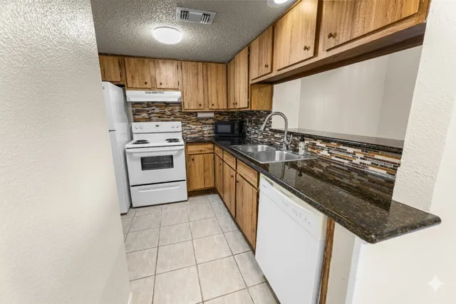 a kitchen with granite countertop a stove sink and cabinets