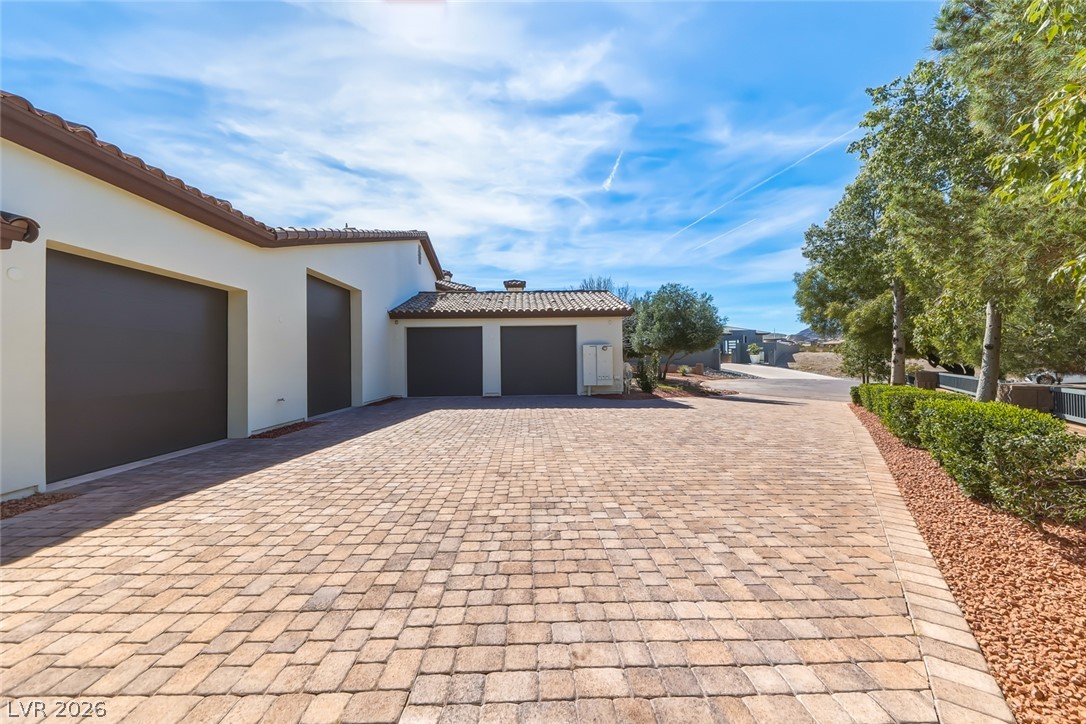 1140 Julie Road Henderson, NV 89002 - Photo 15 of 38 A paver driveway leads to multiple garages and RV/boat garages, offering ample parking and curb appeal.