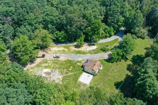 an aerial view of residential house with outdoor space and trees all around