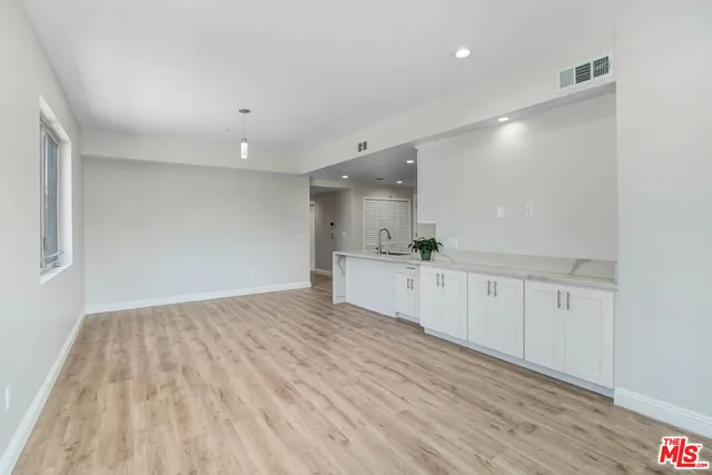 a view of a kitchen with white cabinets and wooden floor