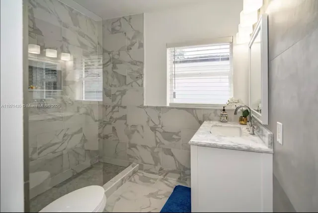 a bathroom with a granite countertop sink a toilet and shower