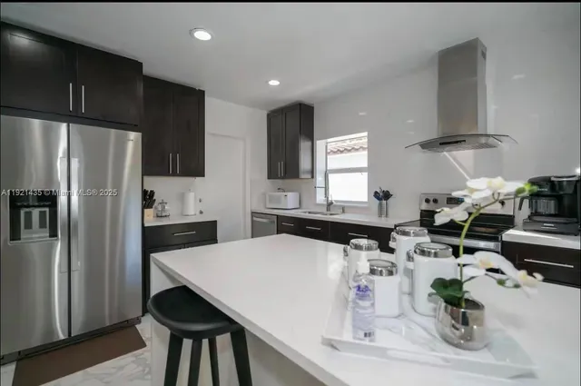 a kitchen with stainless steel appliances a sink a stove a refrigerator and cabinets