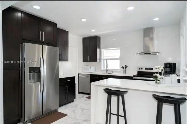 a kitchen with stainless steel appliances a sink a stove a refrigerator and cabinets