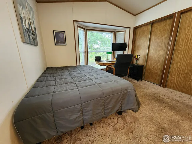 a bedroom with a bed a large window with table and chair