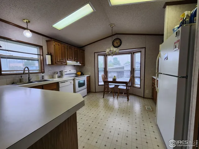 a kitchen with stainless steel appliances granite countertop a refrigerator a sink dishwasher a stove and white countertops with wooden floor