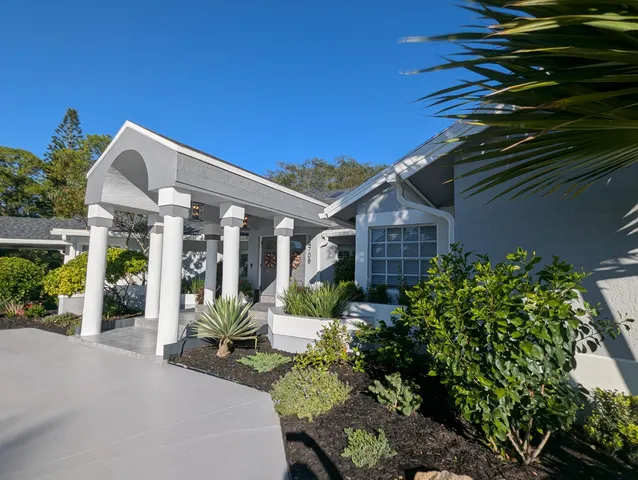 a front view of a house with a garden and trees