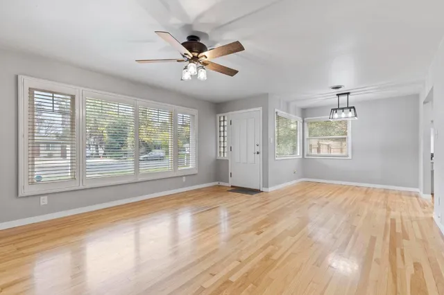 a view of an empty room with a window and wooden floor