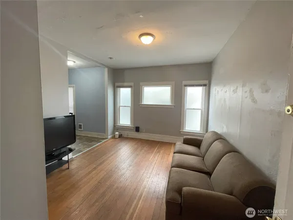 a living room with furniture a flat screen tv and wooden floor