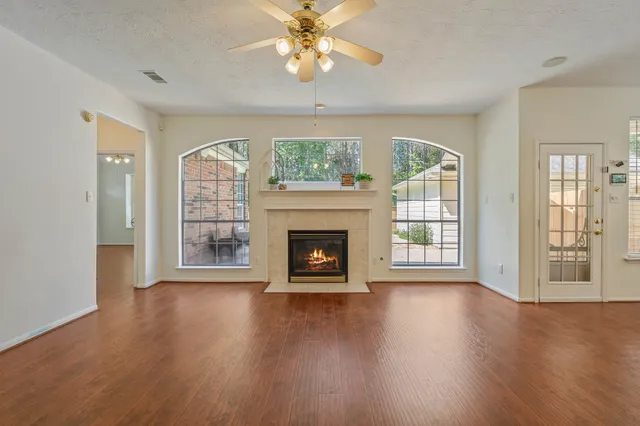 a view of an empty room with wooden floor fireplace and a window
