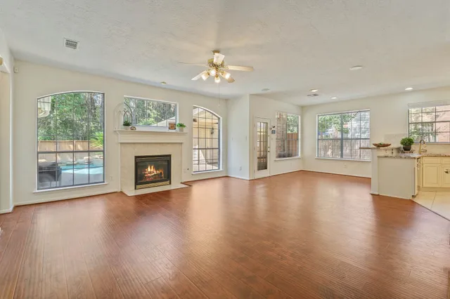 an empty room with wooden floor fireplace and windows