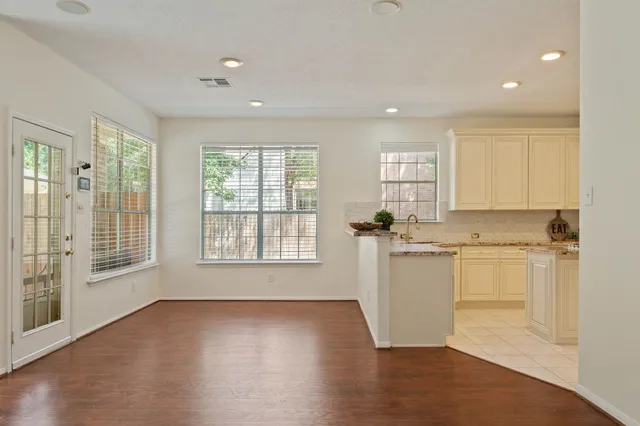 a room with a kitchen island a sink wooden floor and a view of kitchen