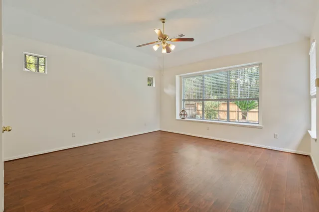 a view of an empty room with wooden floor and a window