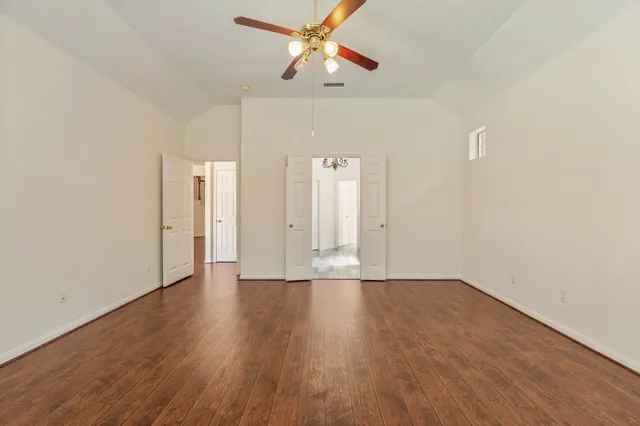 a view of an empty room with window and wooden floor