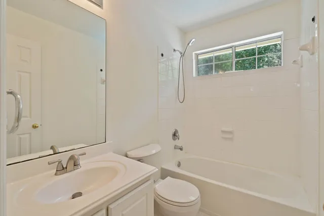 a bathroom with a bathtub shower sink vanity mirror and toilet