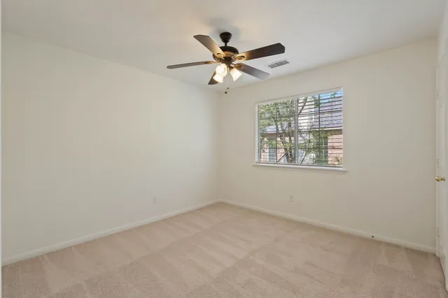 an empty room with a window and a ceiling fan