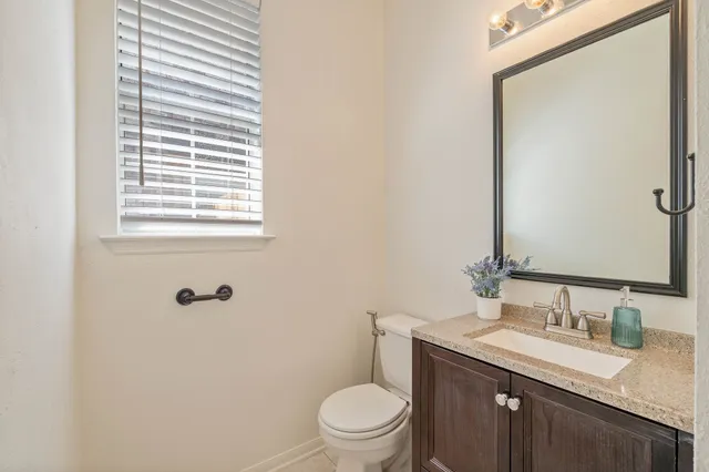a bathroom with a granite countertop sink toilet and mirror