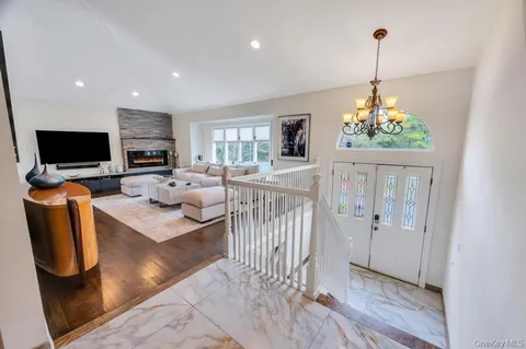 a living room with furniture a flat screen tv and a chandelier