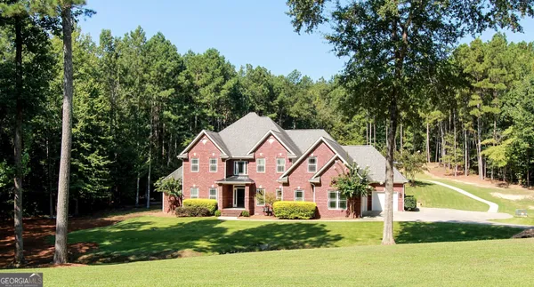 front view of a house next to a big yard and large trees