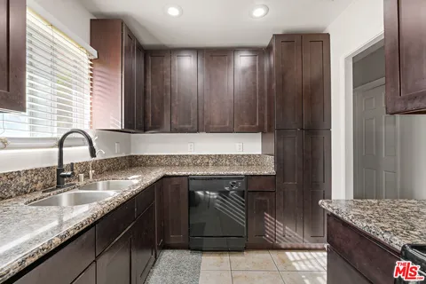 a kitchen with granite countertop stainless steel appliances a sink stove and refrigerator