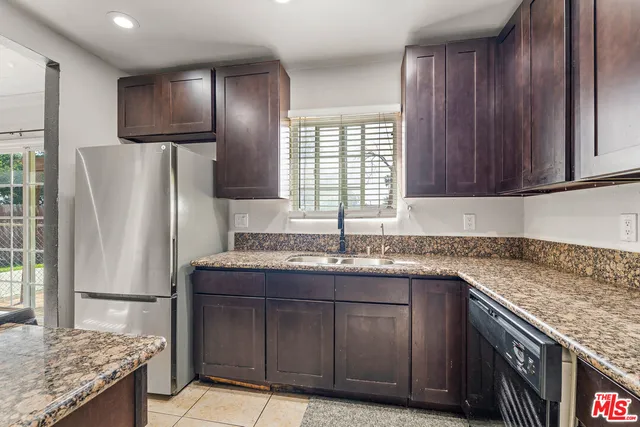 a kitchen with stainless steel appliances granite countertop a refrigerator a stove and a sink with wooden floor