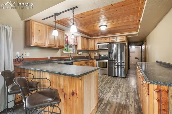 a kitchen with stainless steel appliances granite countertop a sink a stove a refrigerator cabinets and chairs