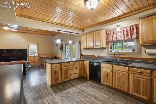 a large kitchen with cabinets chairs and wooden floor