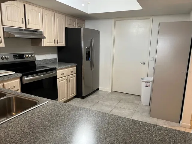 a kitchen with stainless steel appliances granite countertop a refrigerator a stove and a sink