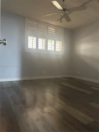 an empty room with windows and fan