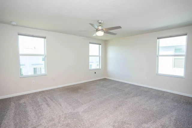 an empty room with a window and ceiling fan