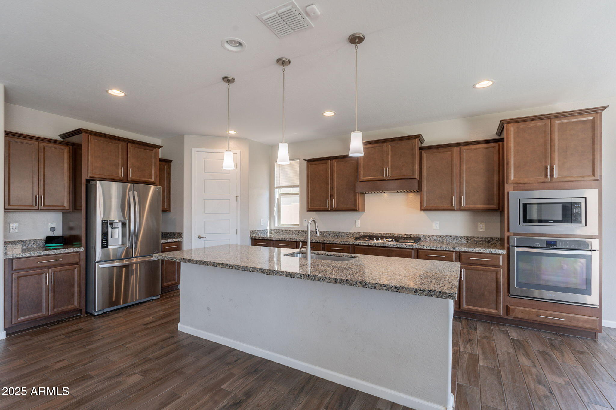 98 North Bay Drive Gilbert, AZ 85233 - Photo 2 of 37 a kitchen with stainless steel appliances wooden floors wooden cabinets a refrigerator and microwave