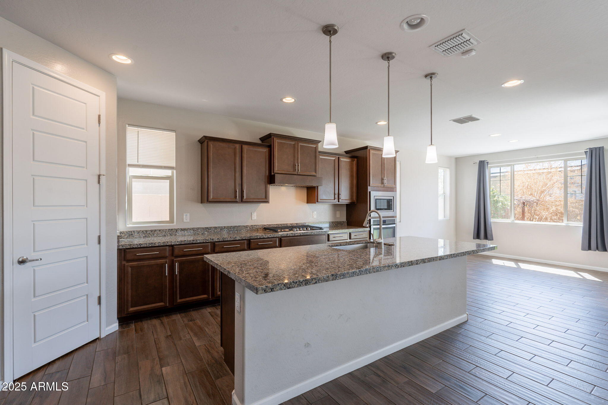 98 North Bay Drive Gilbert, AZ 85233 - Photo 6 of 37 a large kitchen with granite countertop a stove top oven a sink a counter space and wooden floor