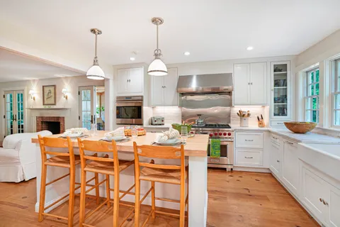 a kitchen with stainless steel appliances kitchen island granite countertop a table chairs and a refrigerator