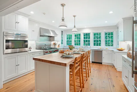 a kitchen with stainless steel appliances kitchen island a large window a sink and cabinets