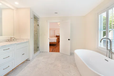 a spacious bathroom with a tub sink and mirror