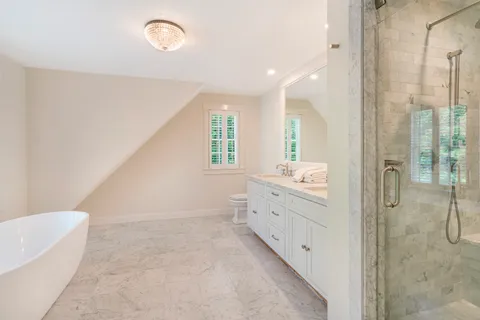 a bathroom with a double vanity sink toilet mirror and bathtub