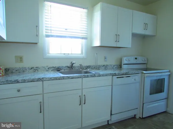 a bathroom with cabinets appliances and a window