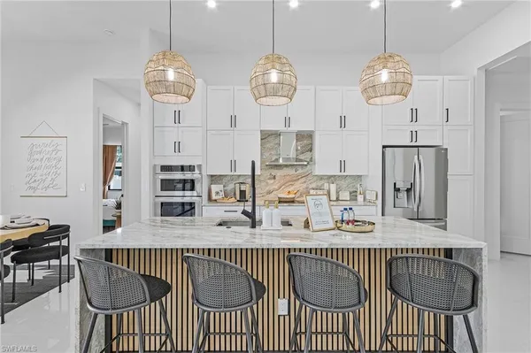 a kitchen with stainless steel appliances granite countertop a sink a stove a dining table and chairs