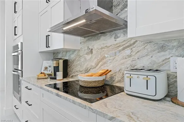 a kitchen with stainless steel appliances granite countertop a sink a stove and white cabinets