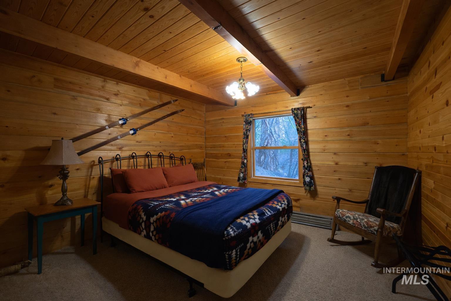 397 Warm Lake Road Cascade, ID 83611 - Photo 23 of 30 Carpeted bedroom with wooden walls, a wood ceiling with exposed beams, and a chandelier